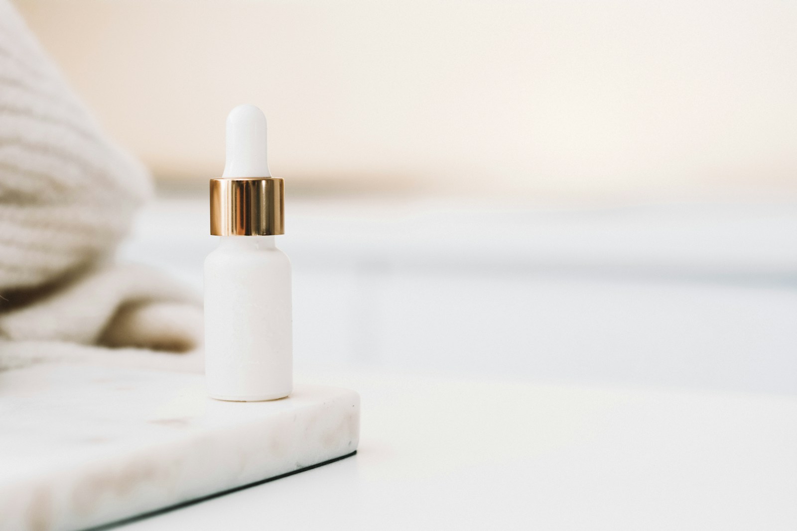 Weisse Pipettenflasche mit Retinol-Serum auf einem Marmoruntersetzer