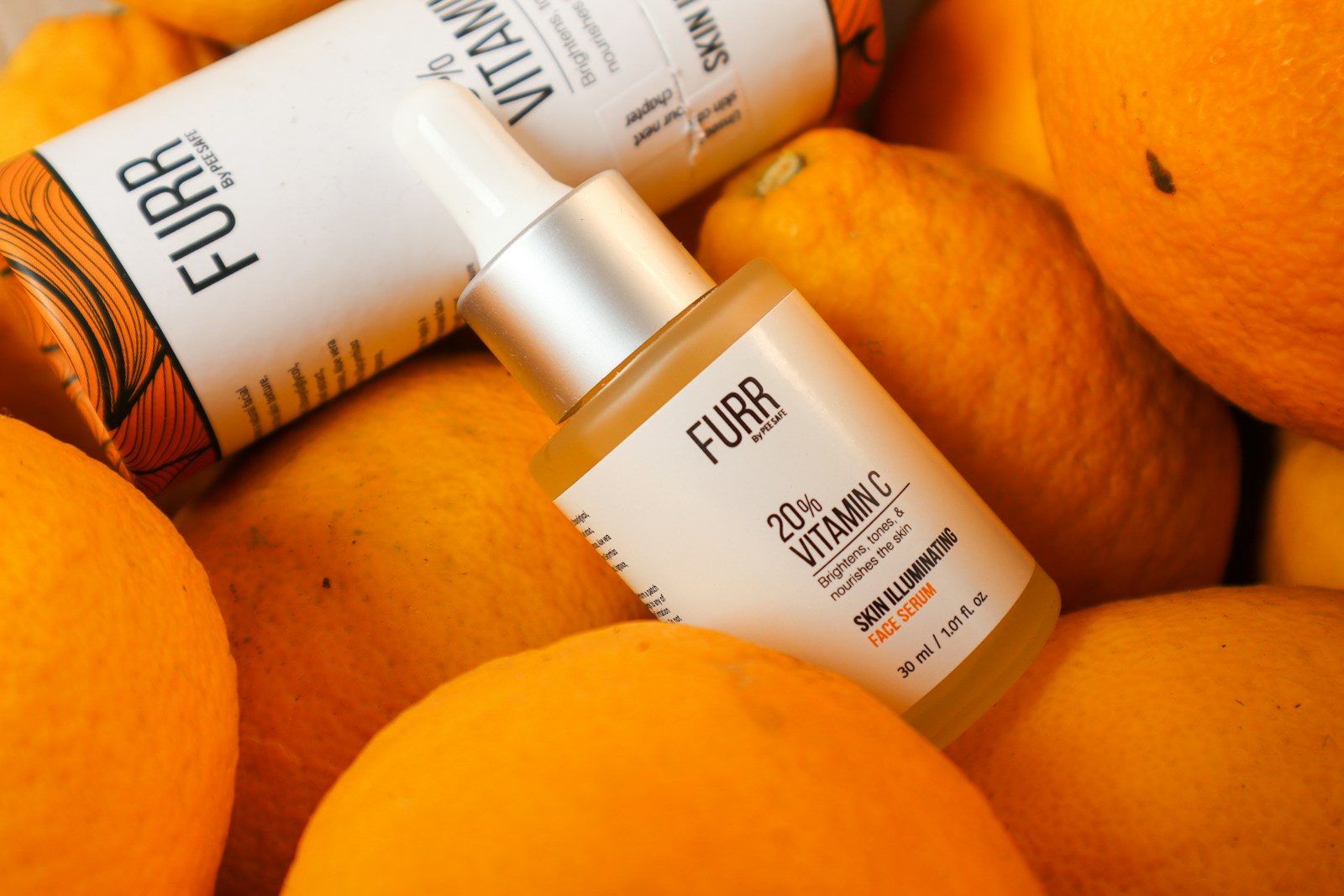 Vitamin C Serumflaeschchen mit Pipette und frischen Zitrusfruechten