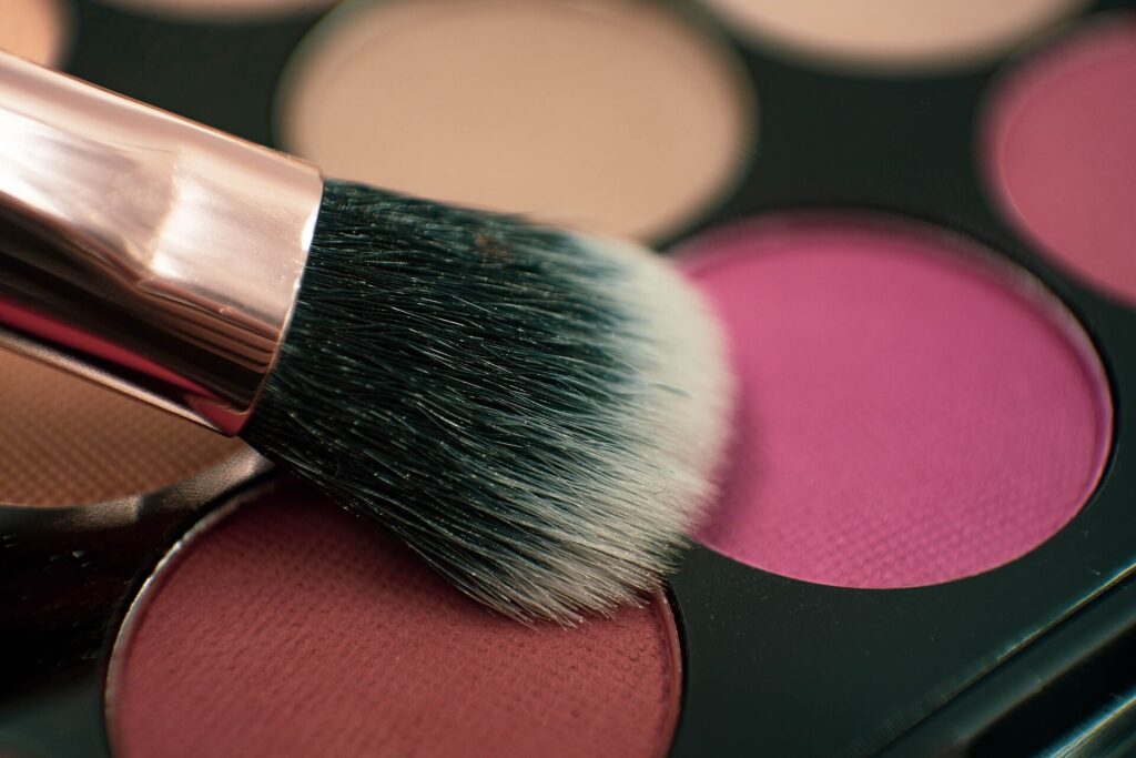 Schmale Lidschattenpinsel liegen nebeneinander auf einer hellen Fl&auml;che neben einer Palette