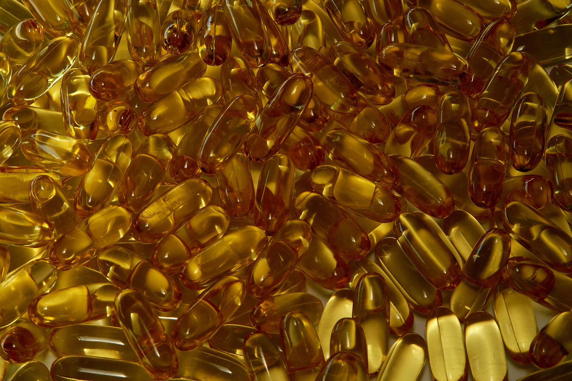 Goldene Ölkapseln liegen neben einer geöffneten Dose auf heller Arbeitsfläche