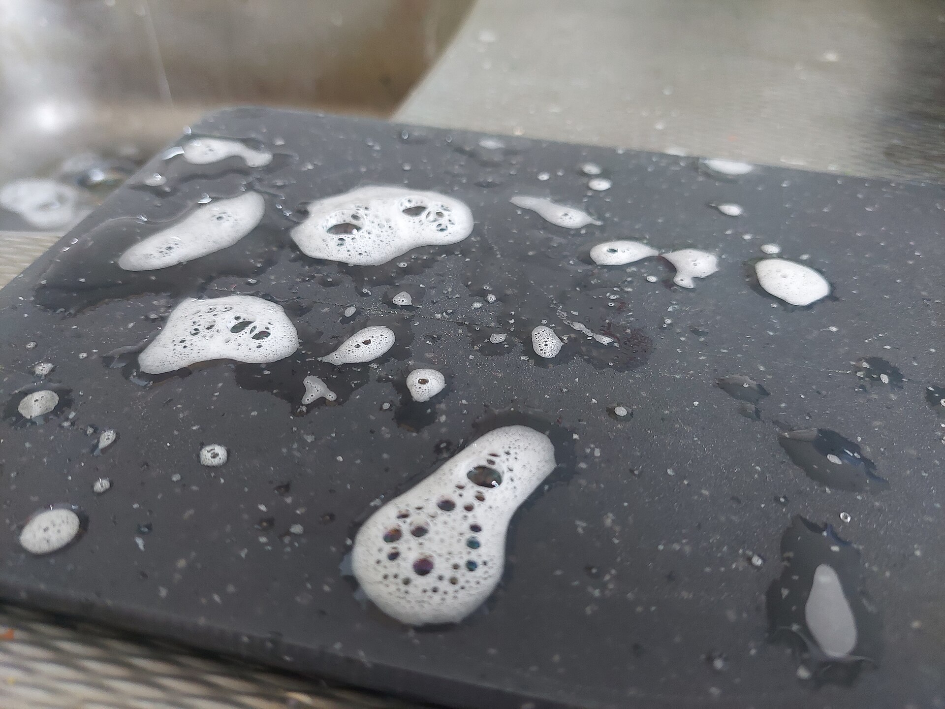 Weißer Schaum in zwei Händen über einem Waschbecken mit laufendem Wasser
