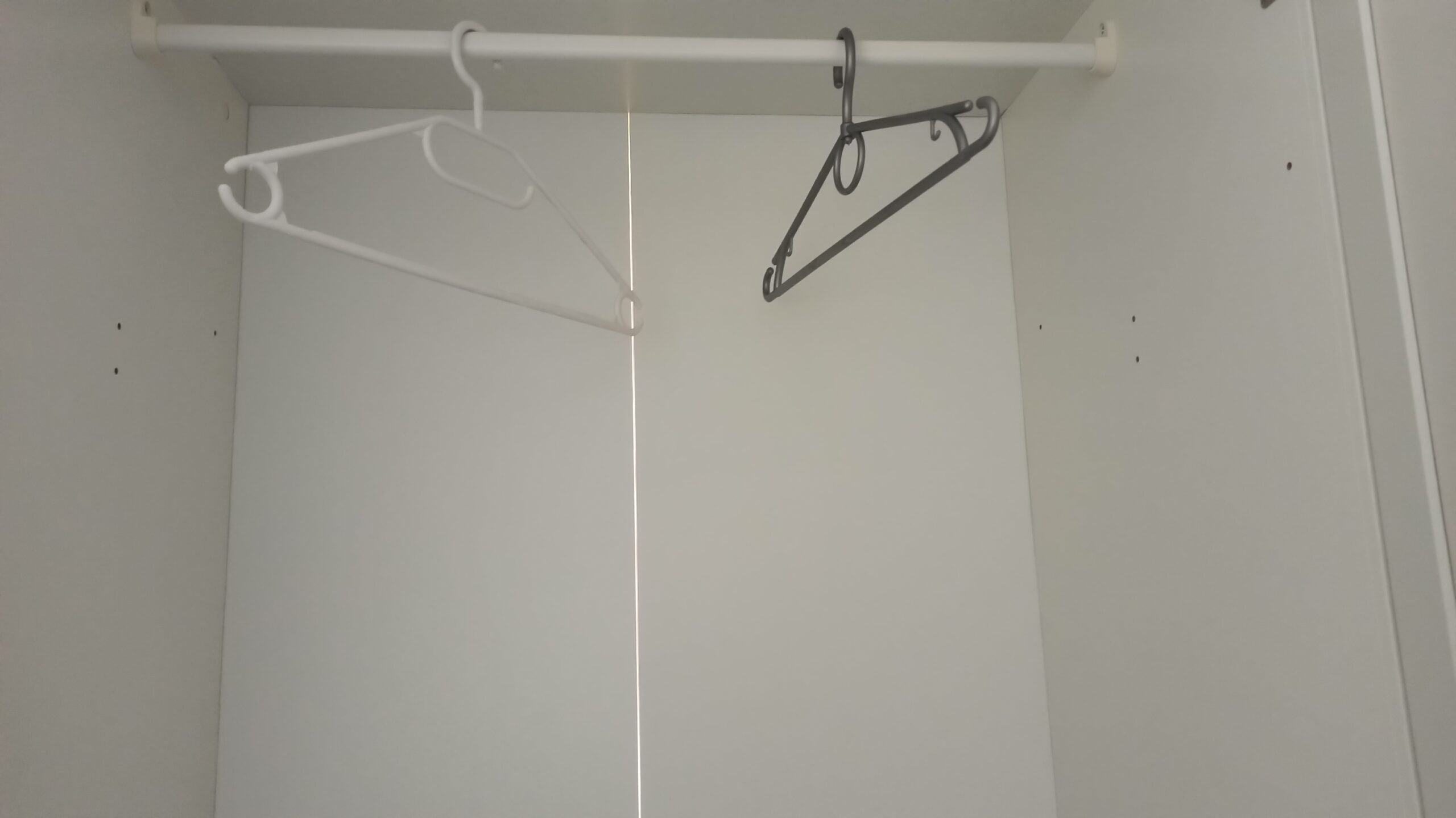 Kleiderstange mit dicht gehängten Blusen, Hemden und Strickteilen in gedeckten Farben