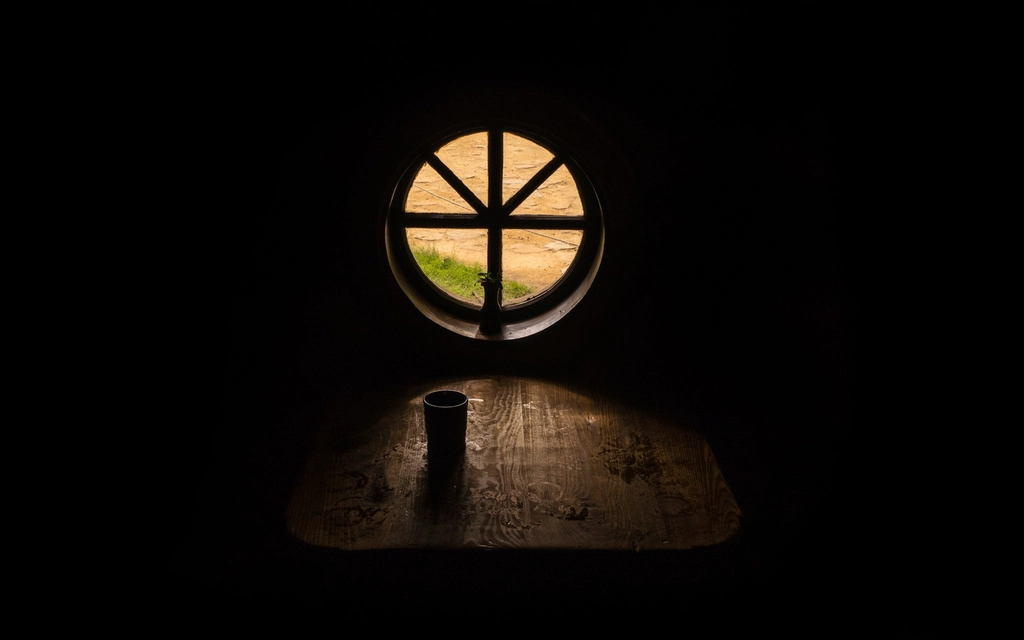Tiefstehende Herbstsonne fällt durch eine Fensterscheibe auf einen hellen Holzboden