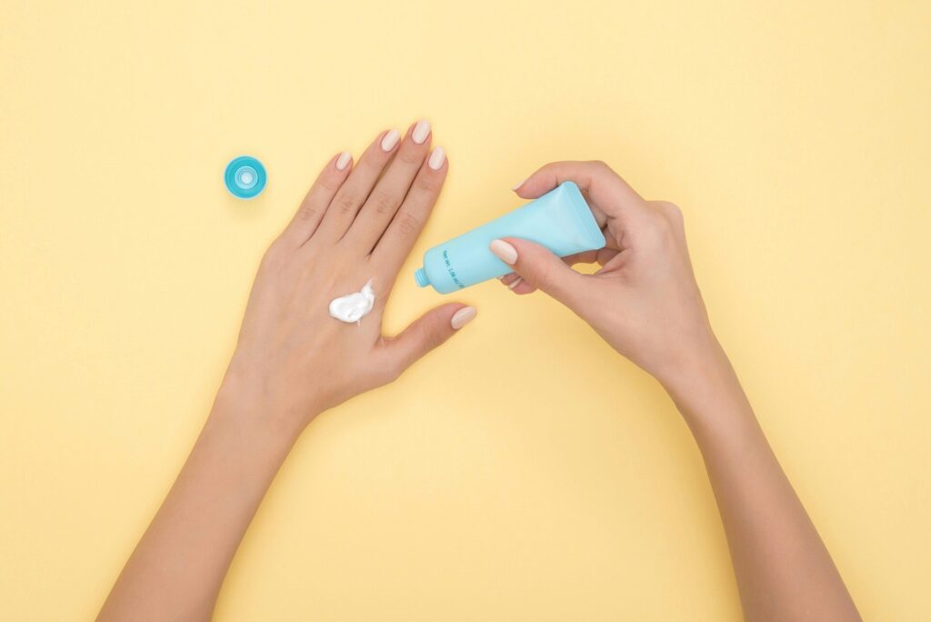 Ge&ouml;ffnete Tube Handcreme mit einem Klecks Creme auf einem Handr&uuml;cken
