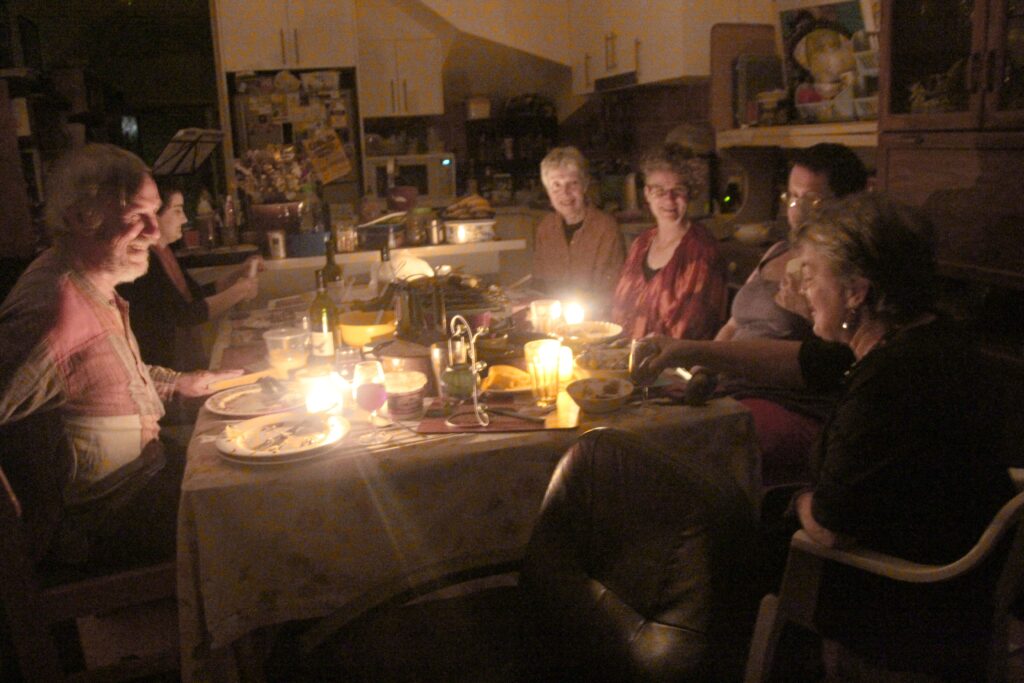 Mehrere brennende Kerzen stehen auf einem festlich gedeckten Tisch am Abend
