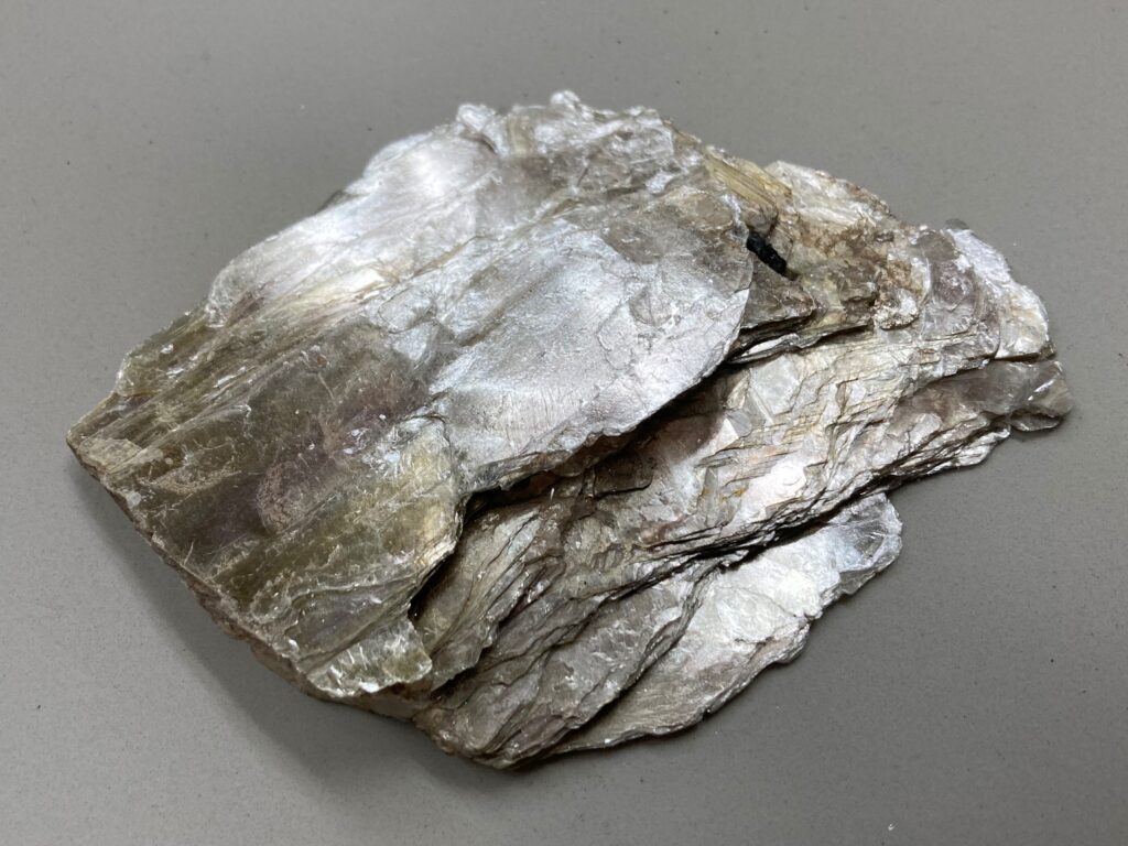 Feine gl&auml;nzende Glimmerpl&auml;ttchen liegen verstreut auf dunklem Untergrund