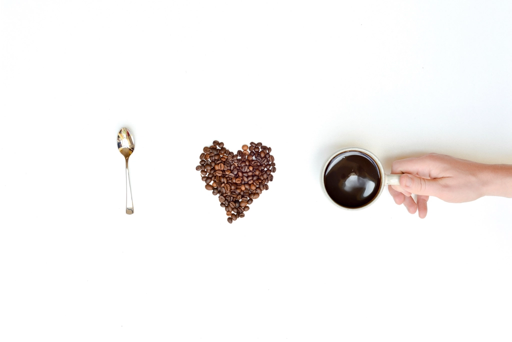 Geröstete Kaffeebohnen liegen auf einem Löffel vor dunklem Hintergrund